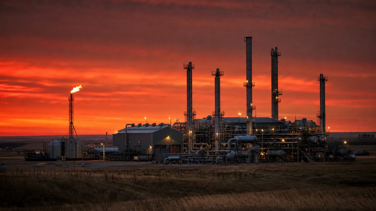 Natural gas processing plant with compressors and flare stack at dusk in western North Dakota