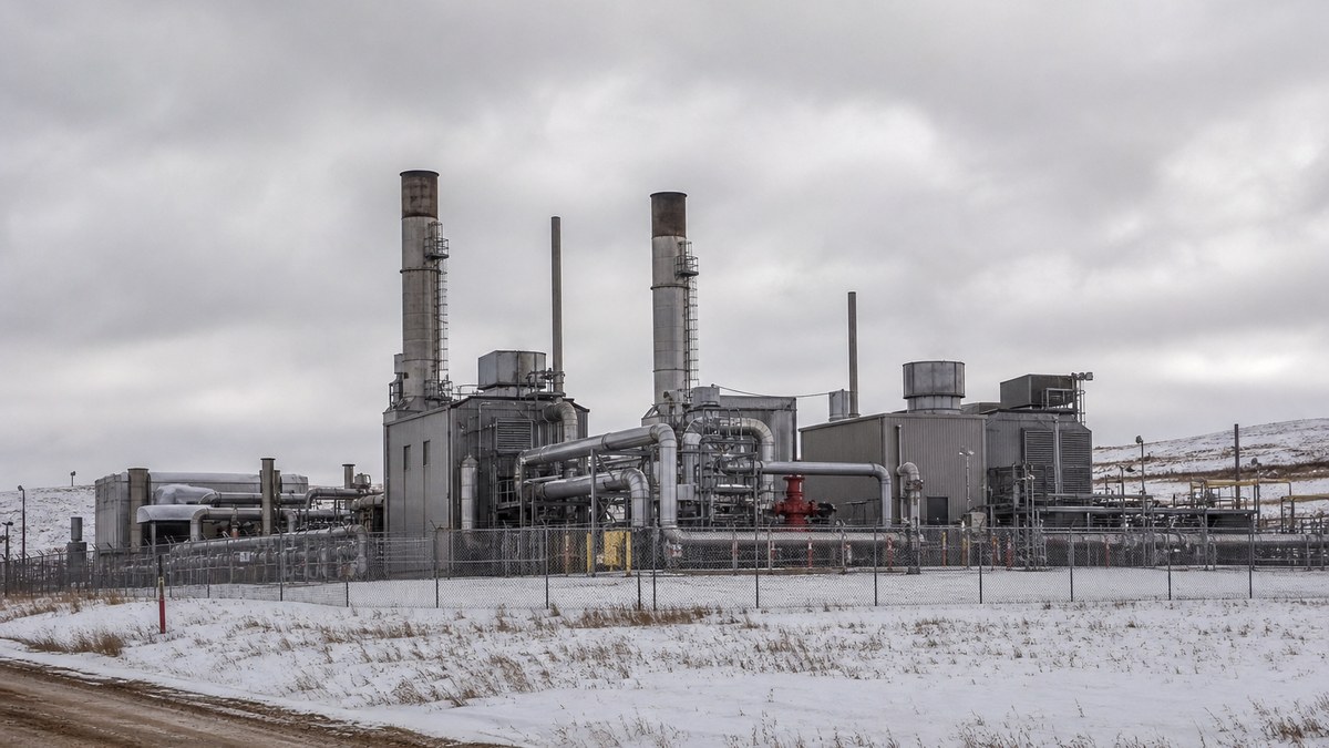 Natural gas compressor station with turbine buildings and piping on the North Dakota prairie under an overcast winter sky
