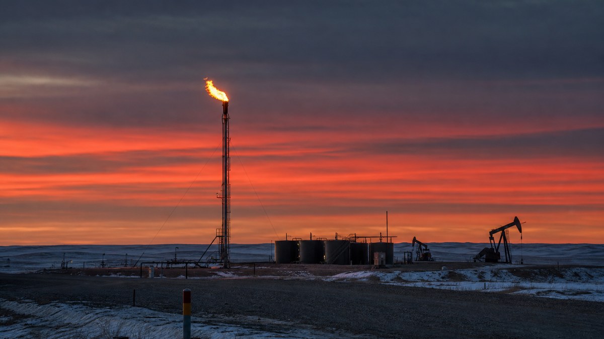 Gas flare stack burning at a Bakken oil well pad at dusk in western North Dakota